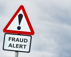 Fraud alert conceptual warning road sign against stormy sky Conceptual triangular hazard road sign against a stormy sky saying fraud alert